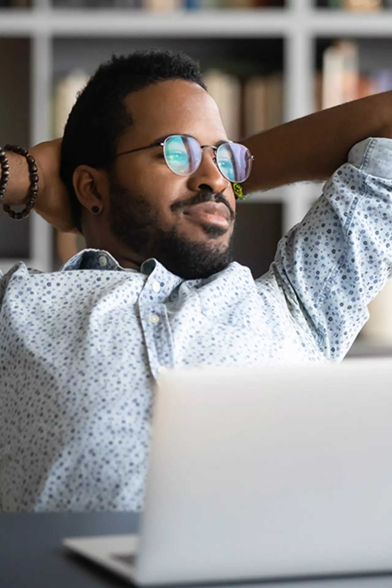 Mann mit Brille sitzt am Arbeitsplatz und schaut aus dem Fenster um die Augen zu entspannen