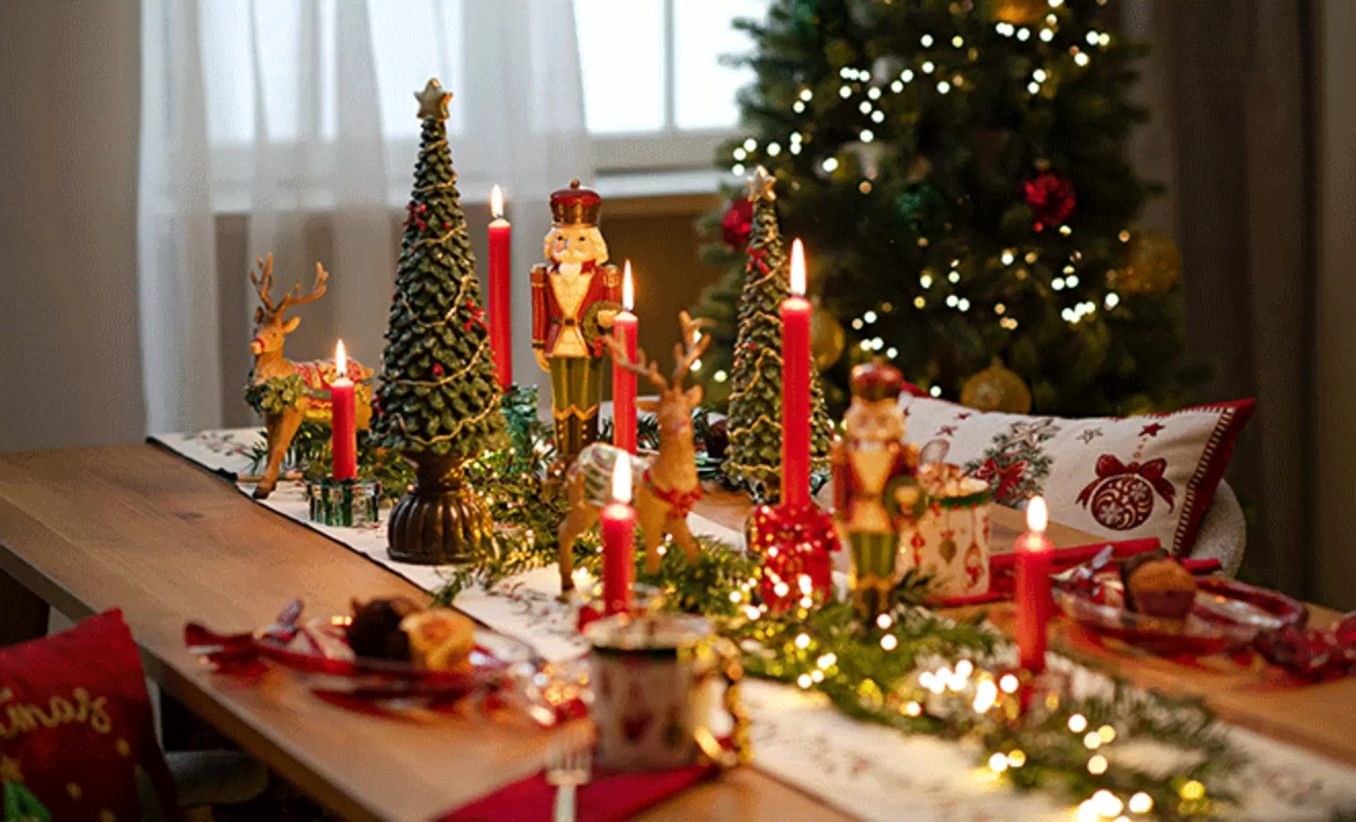 Festlich gedeckter Esstisch mit roten Kerzen, Tannengrün und klassischer Weihnachtsdeko