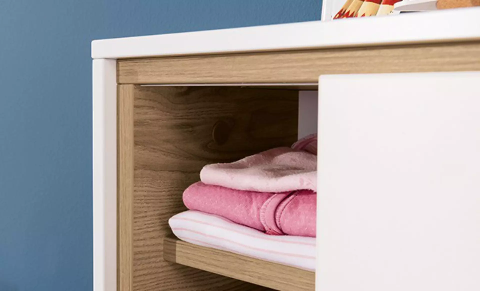 Detailaufnahme eines Wandregals mit Kinderkleidung