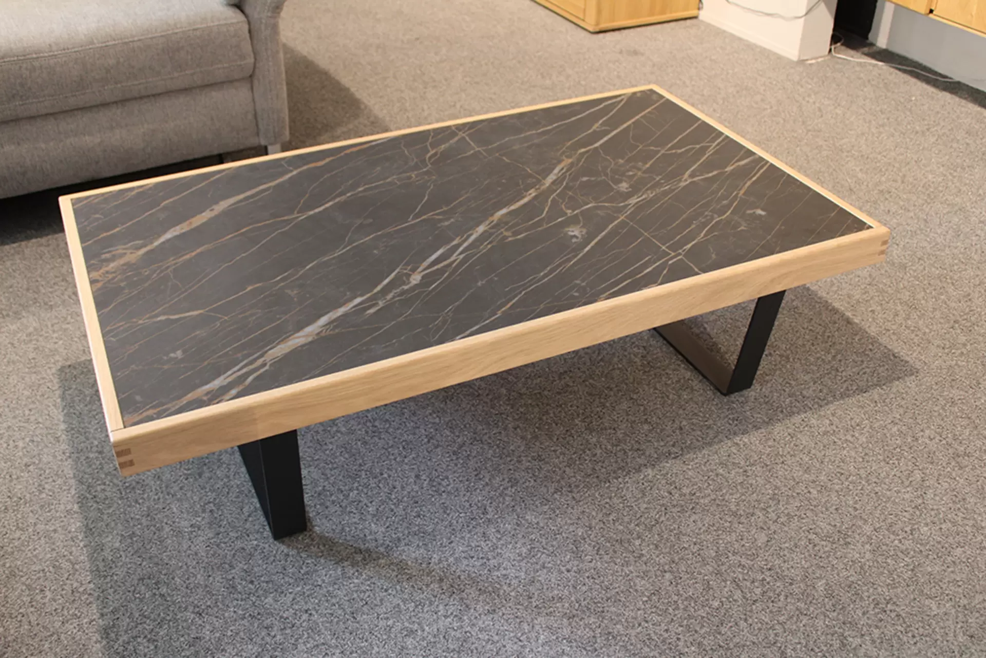 Der Couchtisch TIRANO von Wöstmann aus Holz mit Metallbeinen und Marmor-Platte