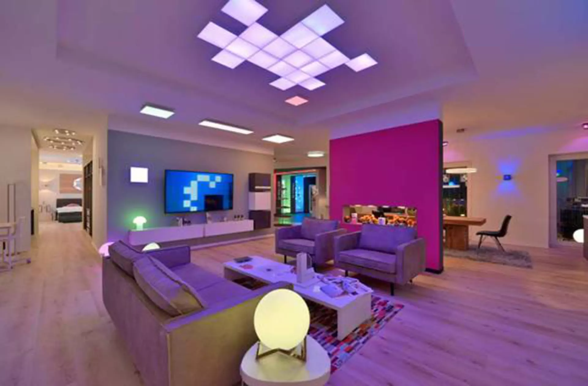 Ein junges Wohnzimmer in buntes Licht getaucht als Milieubild für den Inspirationsbereich "Smart Home".