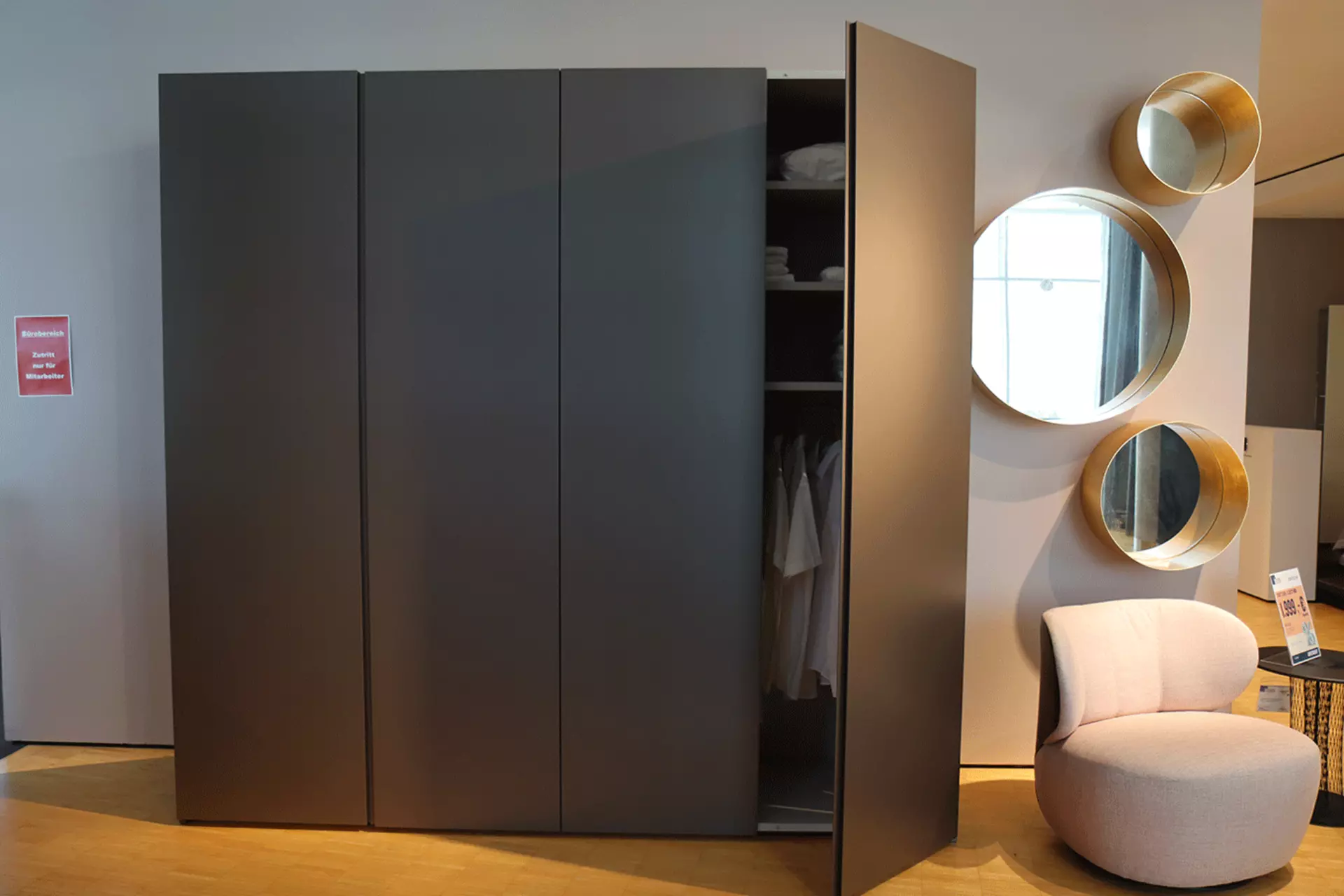 Der interlübke Collect Plus Kleiderschrank in Bronze Metallic mit halboffener Tür frontal aufgenommen. Verfügbar bei interni by Inhofer in Senden