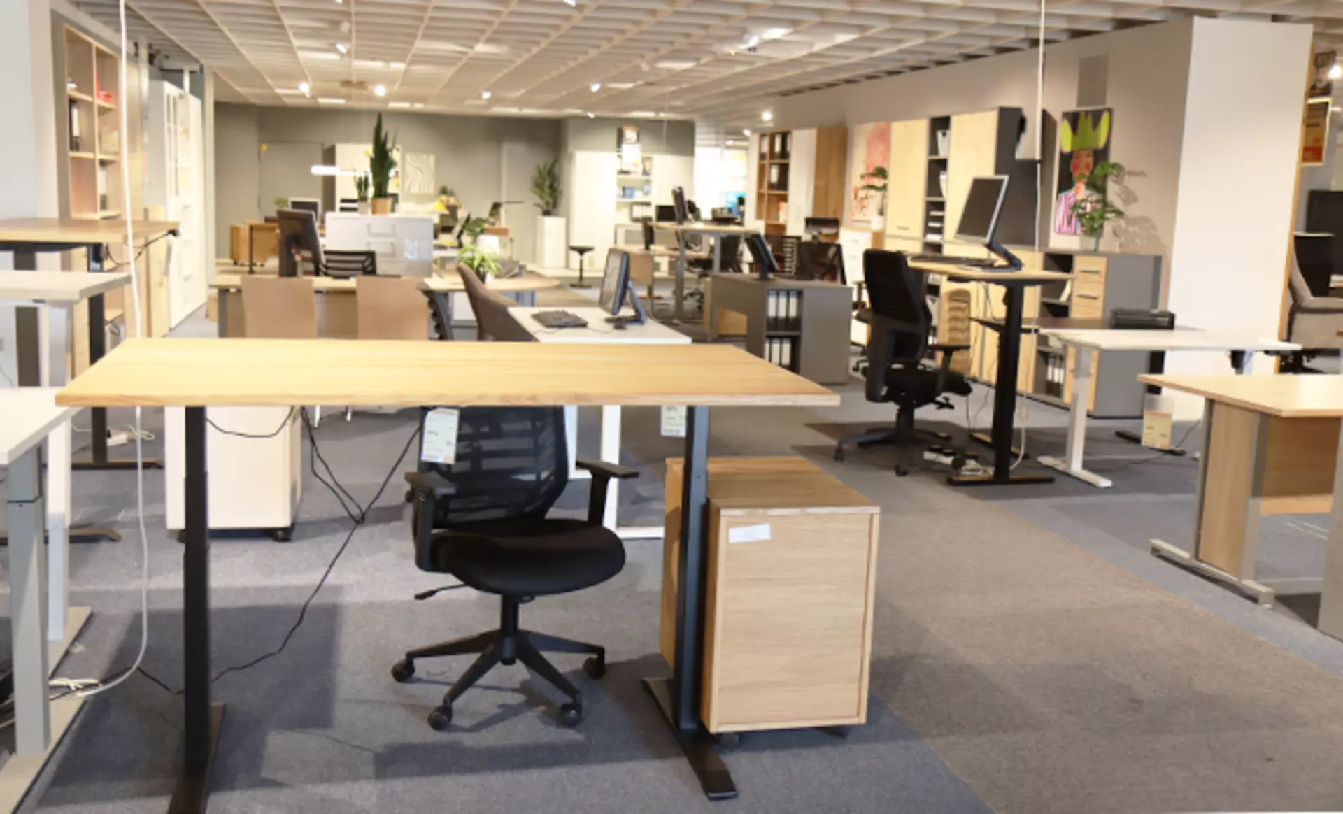 Büroausstellung mit modernen Schreibtischen, Bürostühlen und Stauraummöbeln.
