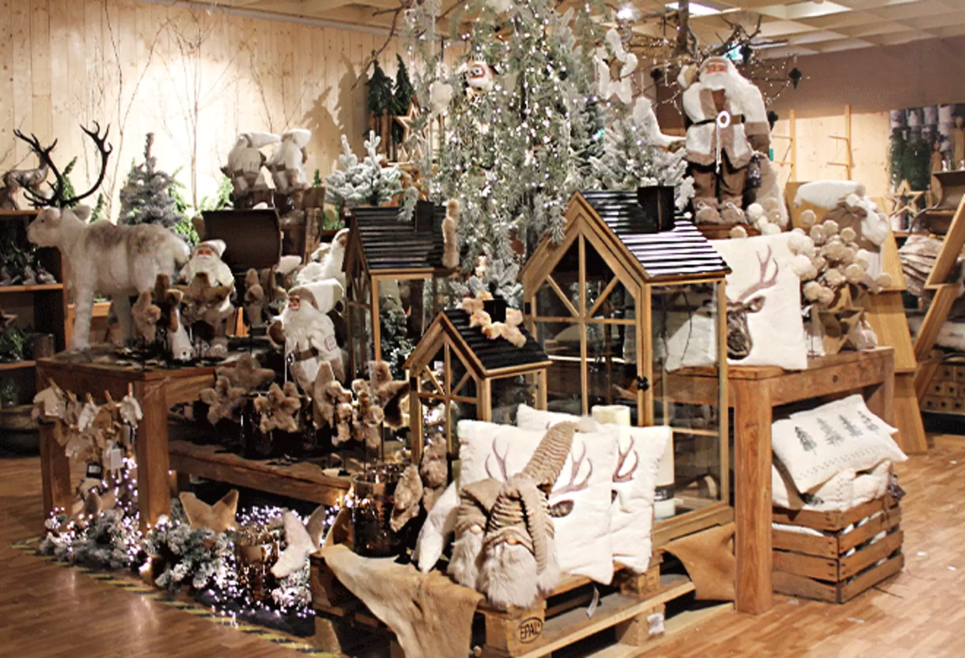 Gemütliche Weihnachtsdeko aus Holz mit Windlichtern, Dekohäusern und Plüschkissen auf Holz-Präsentationsbänken
