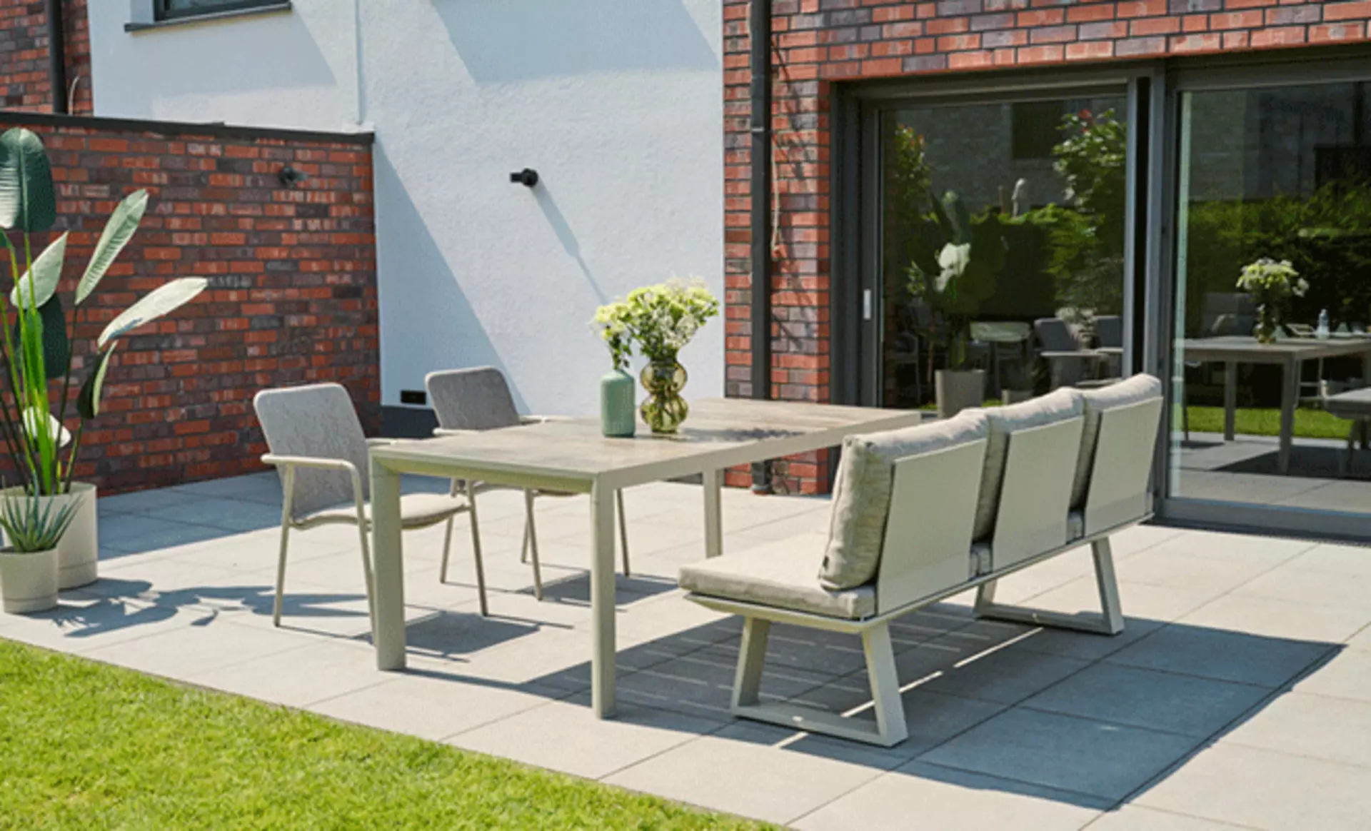 Schöne Terrasse mit dekoriertem Gartentisch und Sitzbank