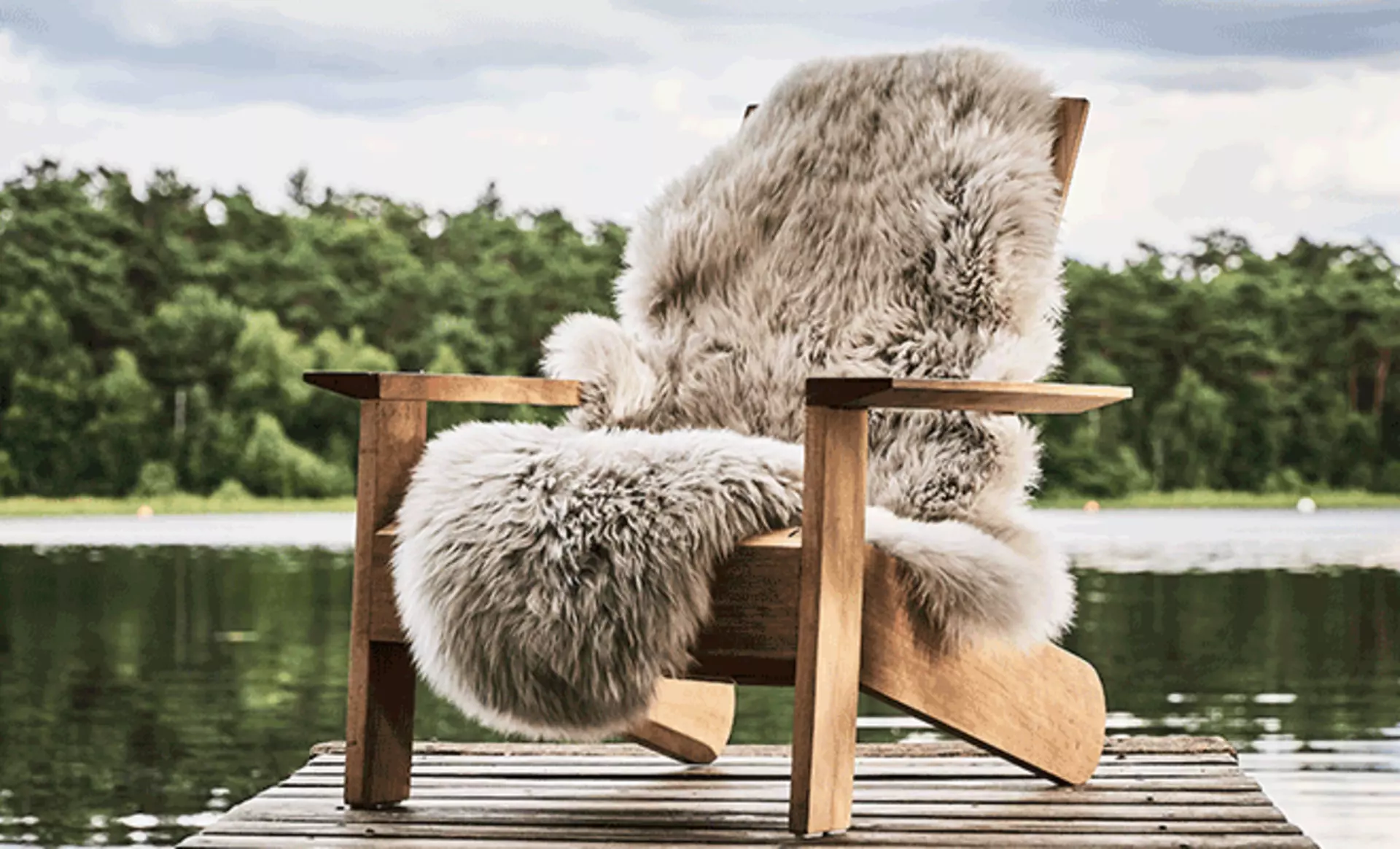 graues Sitzkissen aus Fell auf einem Holzstuhl