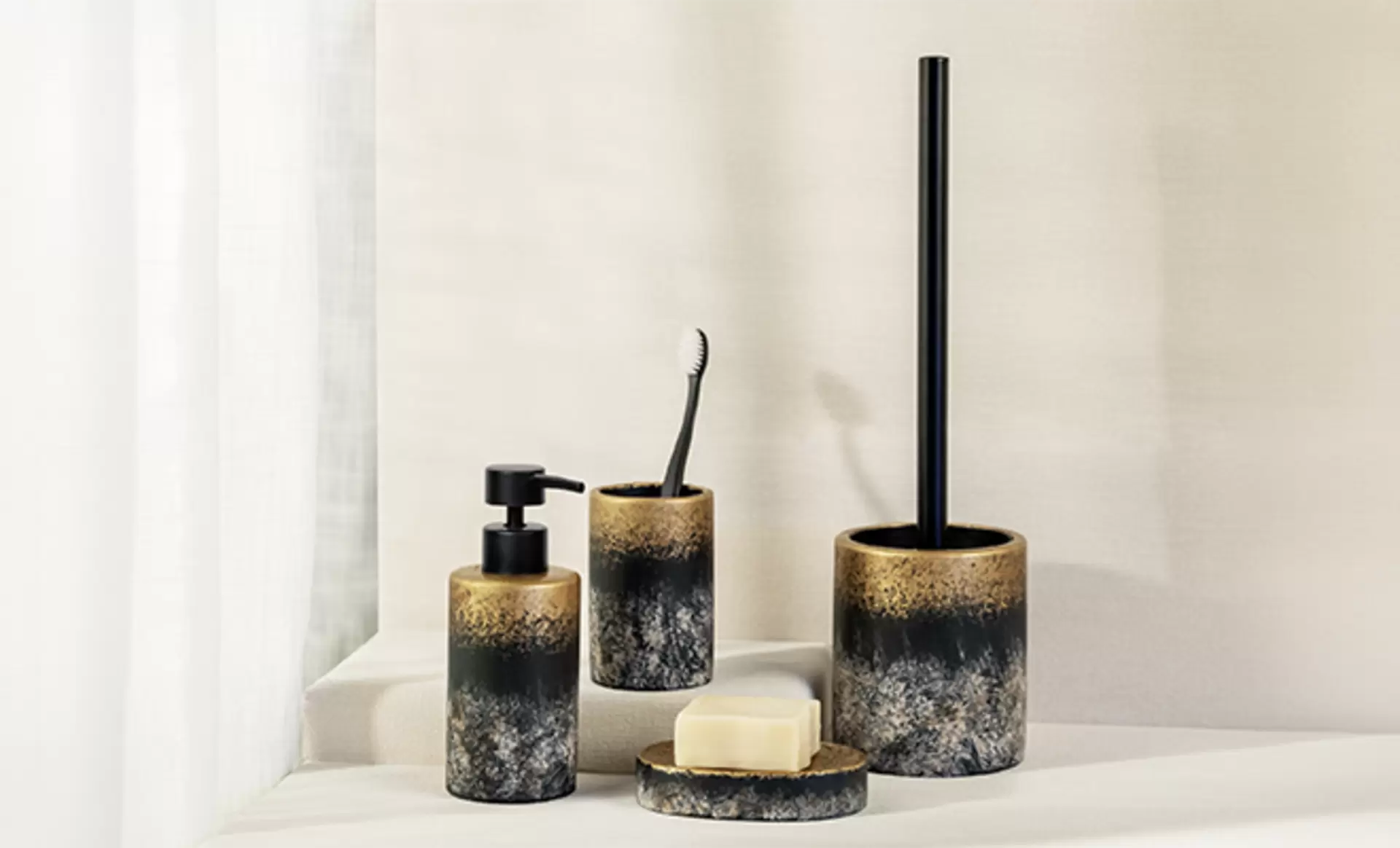 Ein Wenko Badezimmerset in schwarzer Marmoroptik mit goldenem Rand für Seife, Zahnbürste und WC Bürste