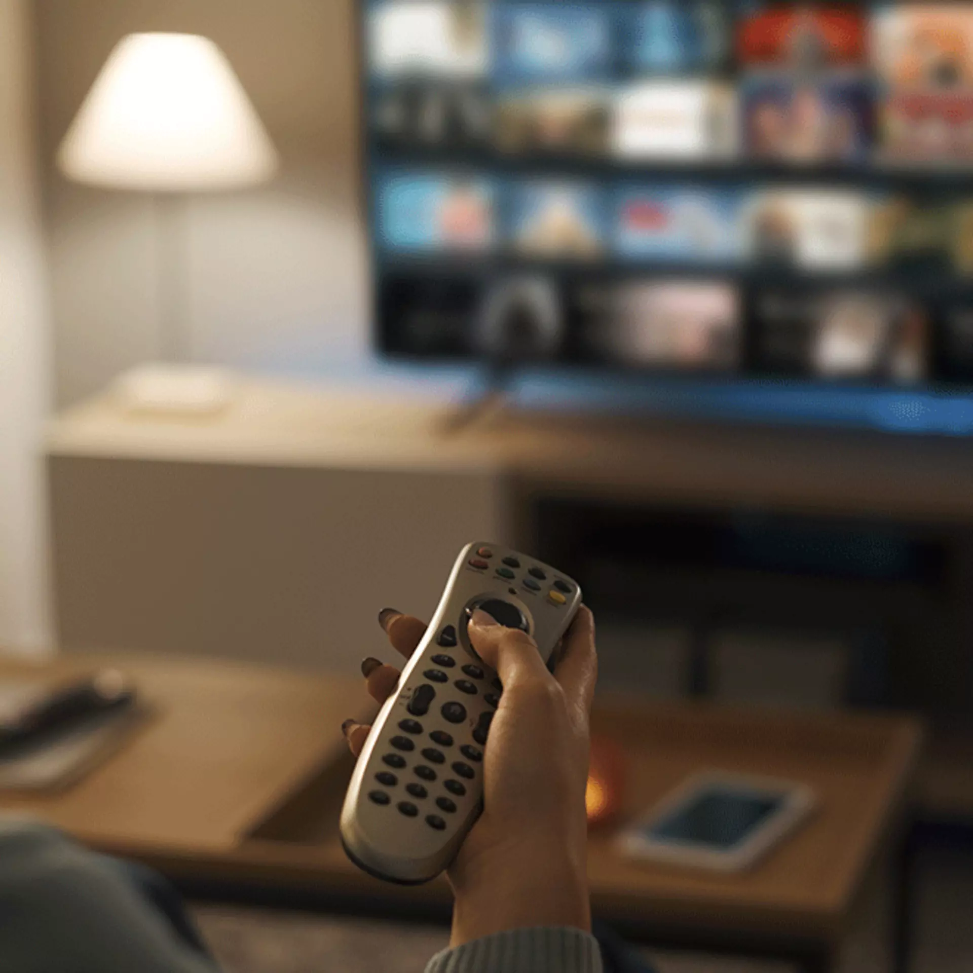 Fernbedienung in der Hand einer Person, die den Fernseher bedient