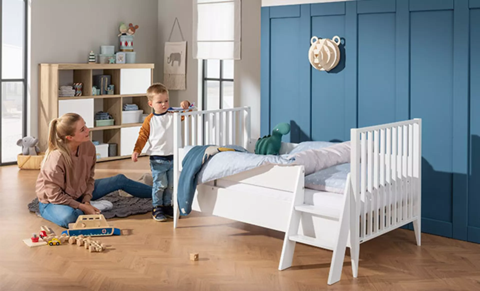 Flexibles Kinderzimmer mit weißem Juniorbett und viel Stauraum für Spielzeug.