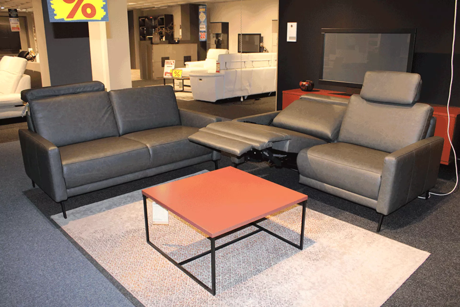 Polstergarnitur in Grau das Mit Kopfstützen versehen sind und eins der Sitze nach hinten gelehnt ist 