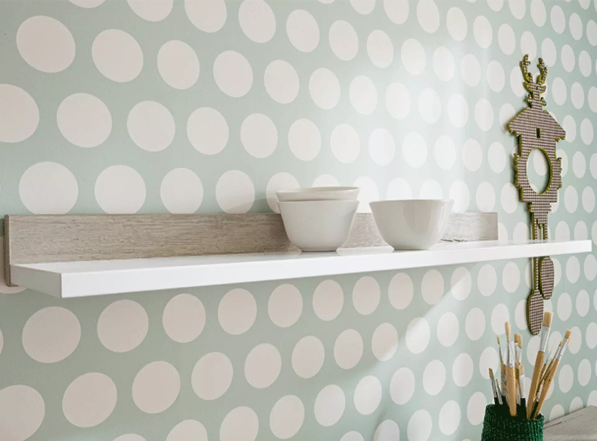 weißes wandregal mit tassen als dekoration an einer weiß-grauen wand