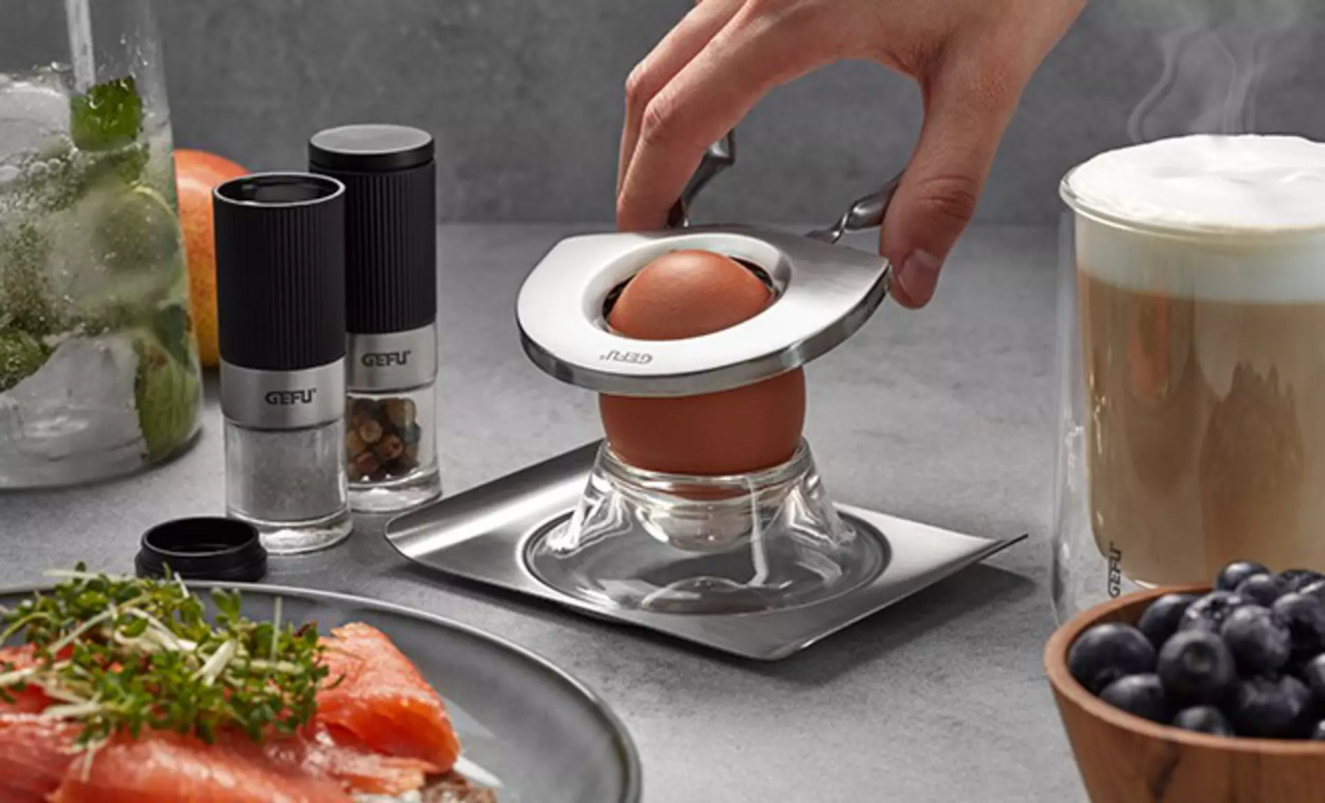 Hand benutzt GEFU Eierköpfer zum Öffnen eines gekochten Eis.