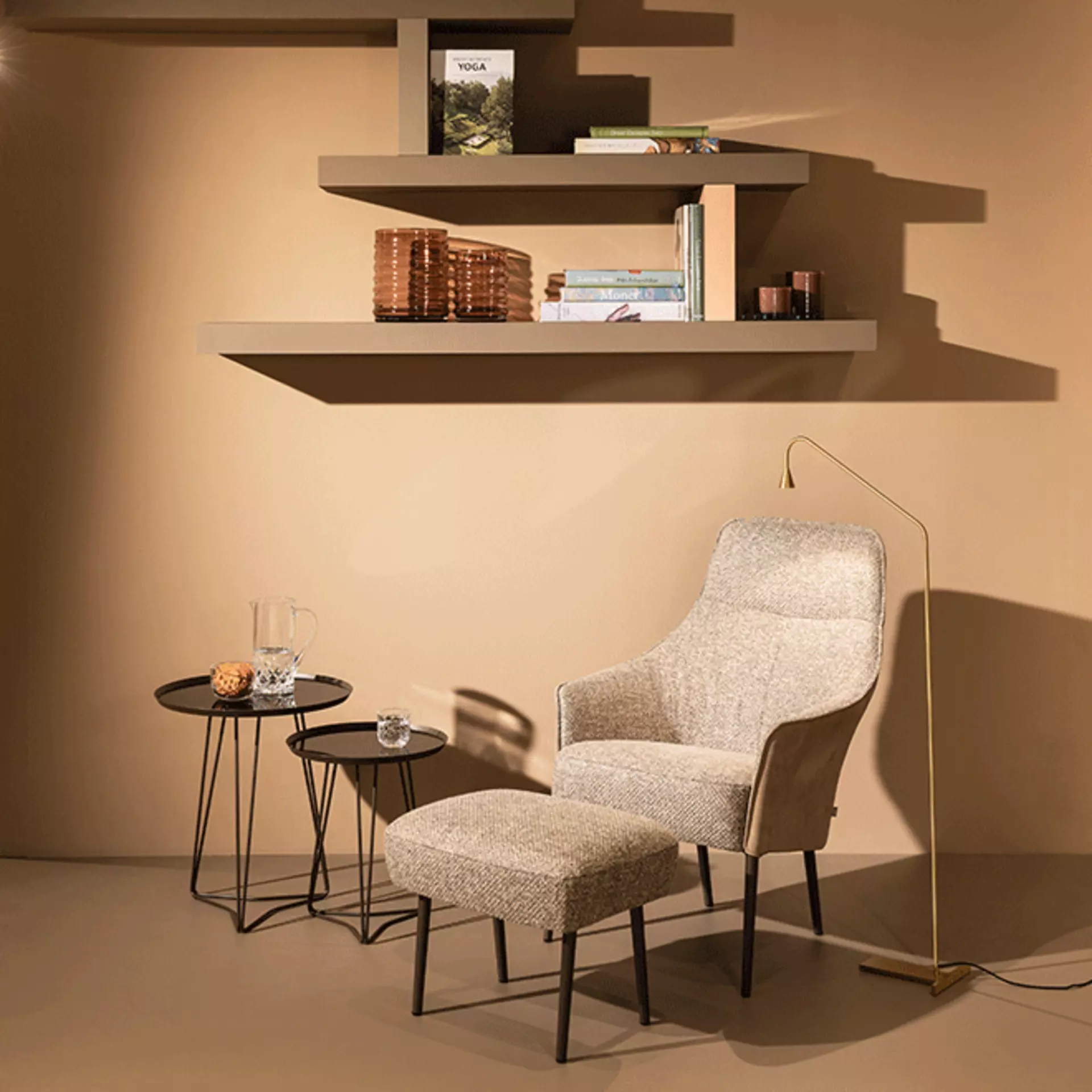 Sitzgelegenheit mit Fußlehne in grau vor einer braunen Wand 