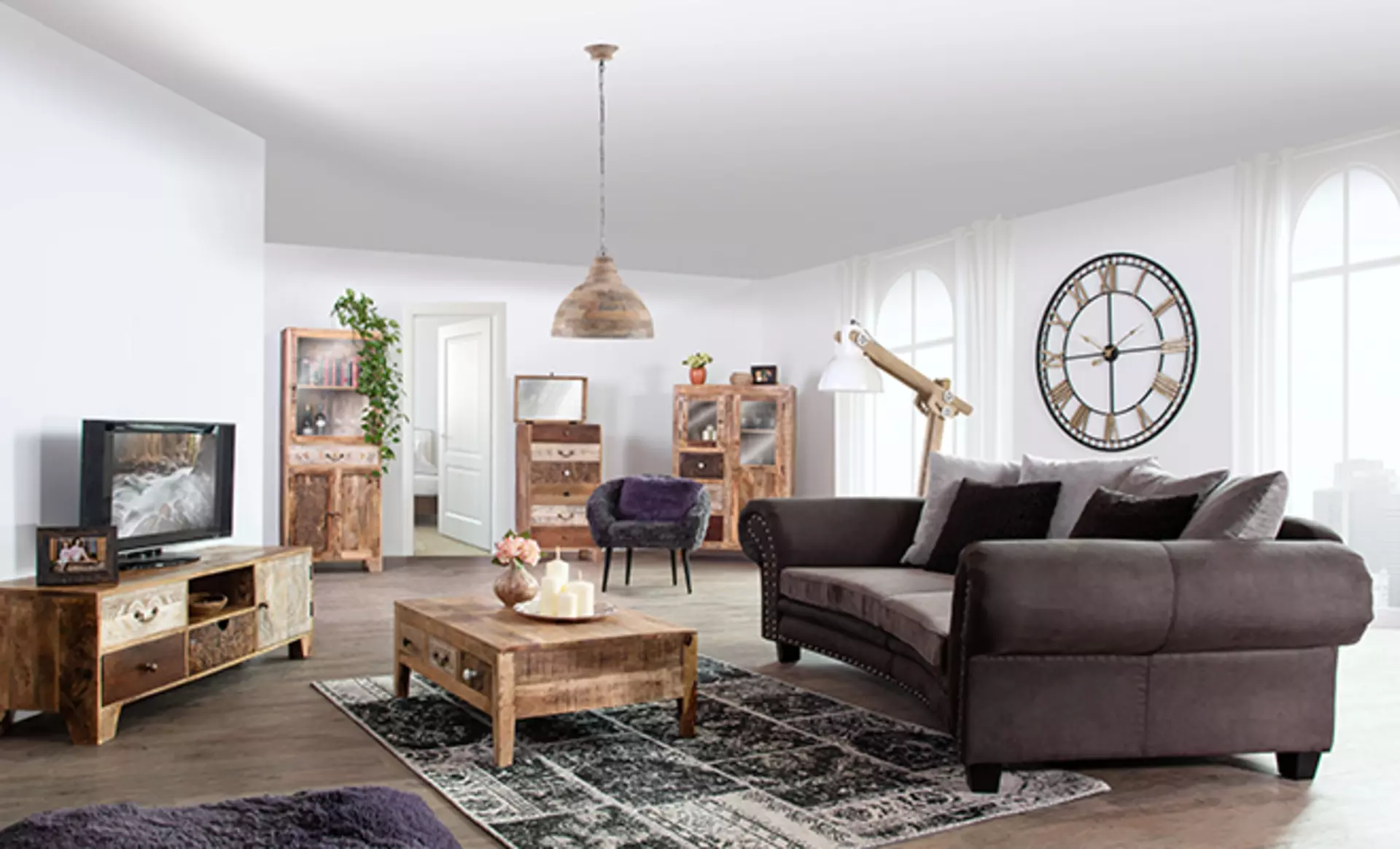 Stilvoll eingerichtetes Wohnzimmer mit Industrial-Möbeln von Gutmann Factory, grauem Ecksofa, Massivholz-Couchtisch, TV-Lowboard, Vitrinen und modernen Wohnaccessoires
