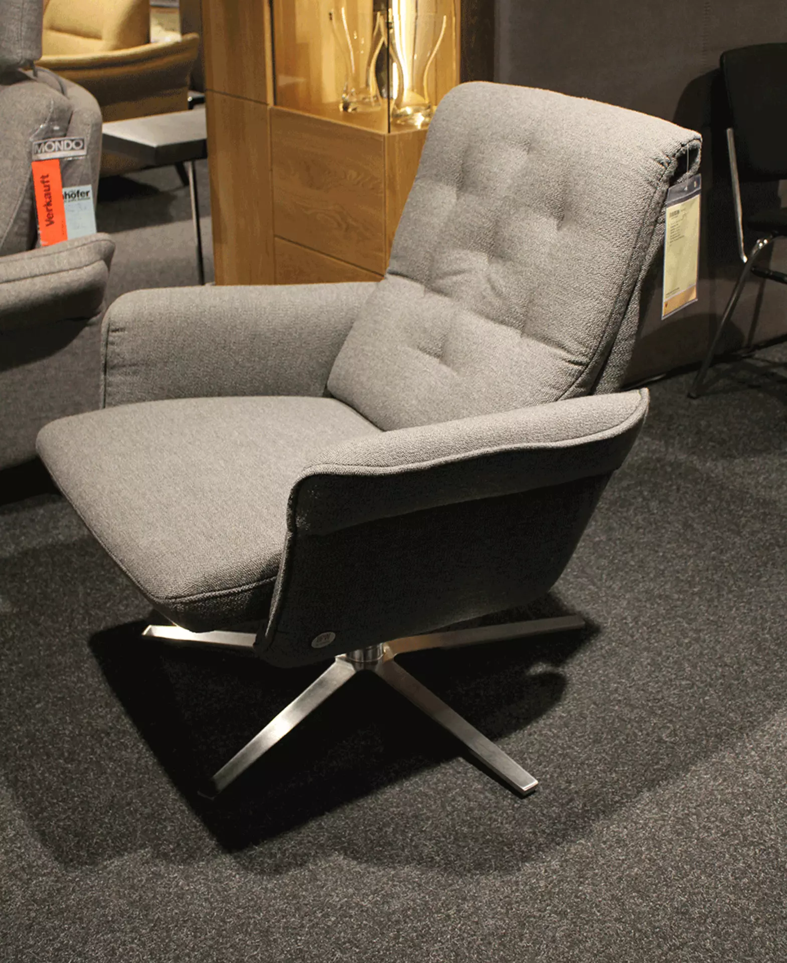 Ein Ausstellungsstück das ein Grauen Sessel von der Seite zeigt 